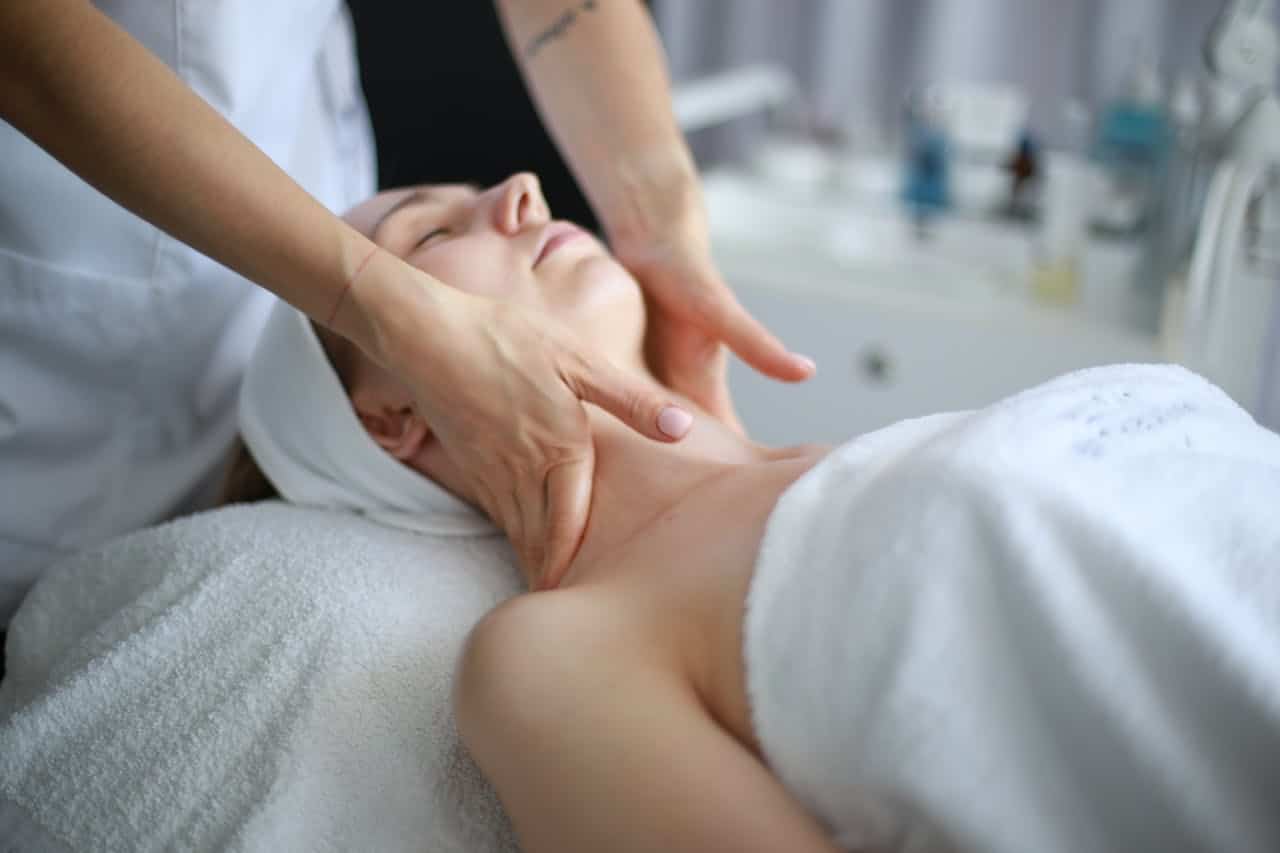 A professional facial massage being performed on a relaxed woman.